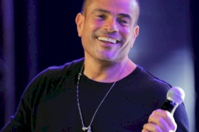 معجبة تلفت انتباه عمرو دياب وتشتته خلال مقابلة تلفزيونية! (شاهد)